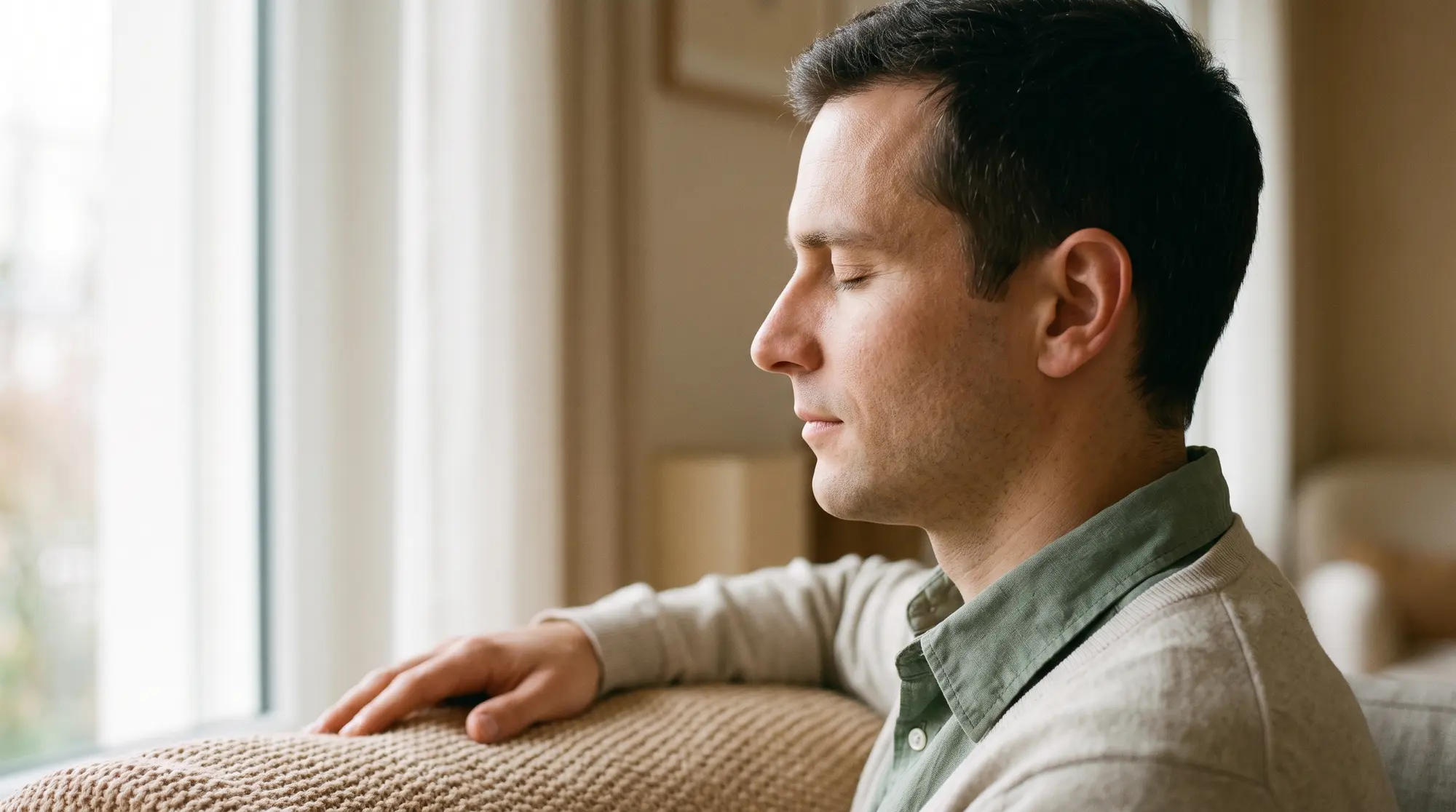 Un homme de profil, les yeux fermés, qui respire calmement près d'une fenêtre.